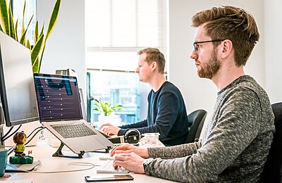 man sitting on chair wearing gray crew-neck long-sleeved shirt using Apple Magic Keyboard